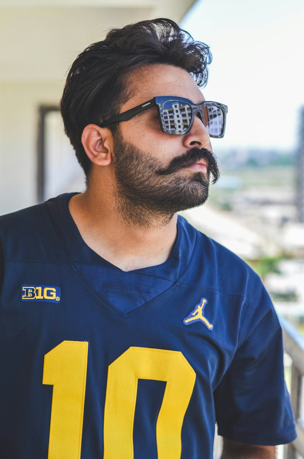 Hombre con camiseta azul y amarilla adidas con cuello en V con gafas de sol negras