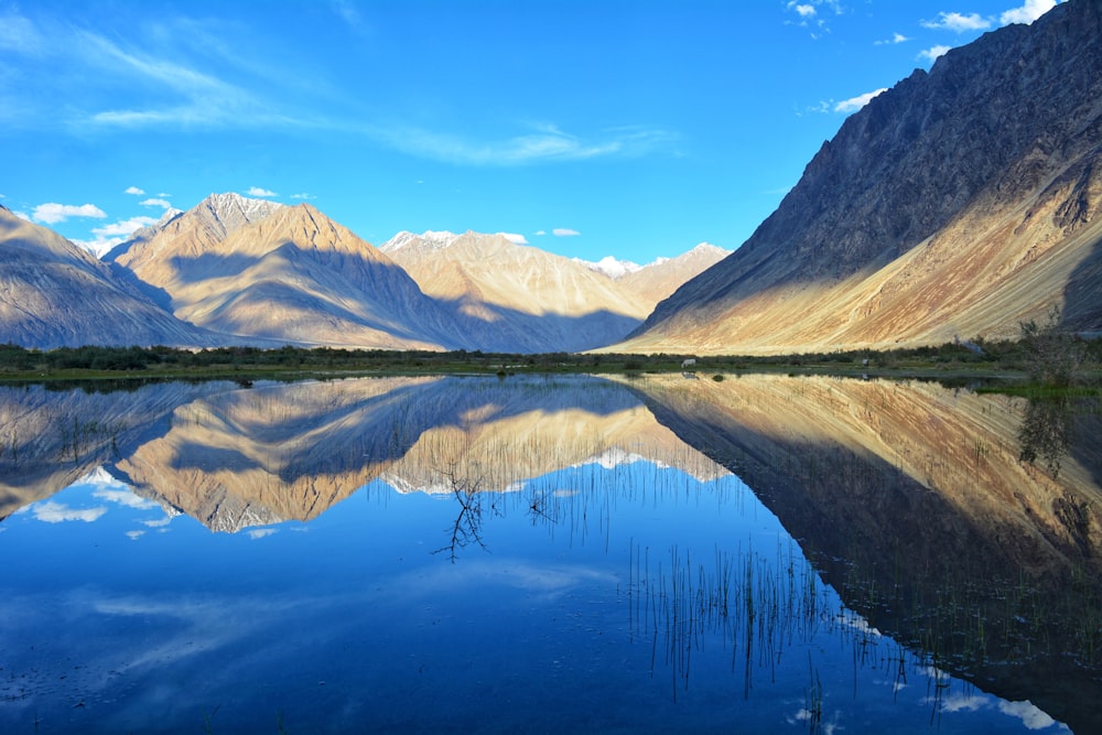 lake near mountain under blue sky during daytime