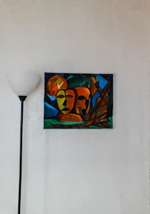 Abstract colorful painting hanging on a minimalist living room wall with natural light.