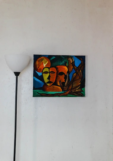 Abstract colorful painting hanging on a minimalist living room wall with natural light.