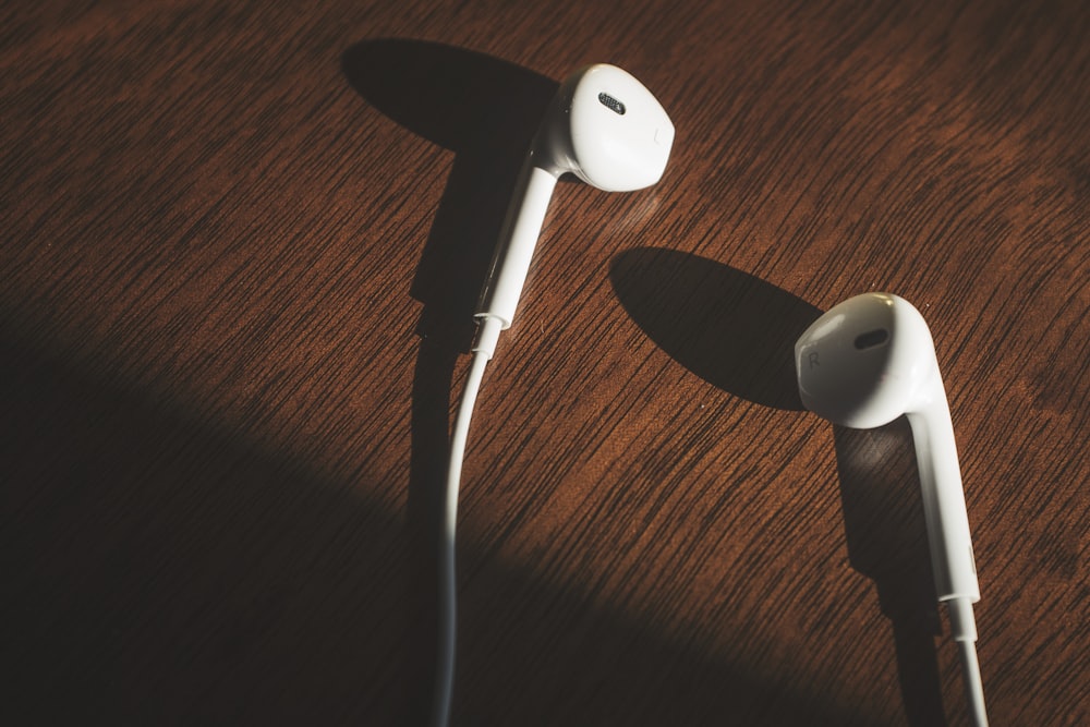 white earbuds on brown wooden table