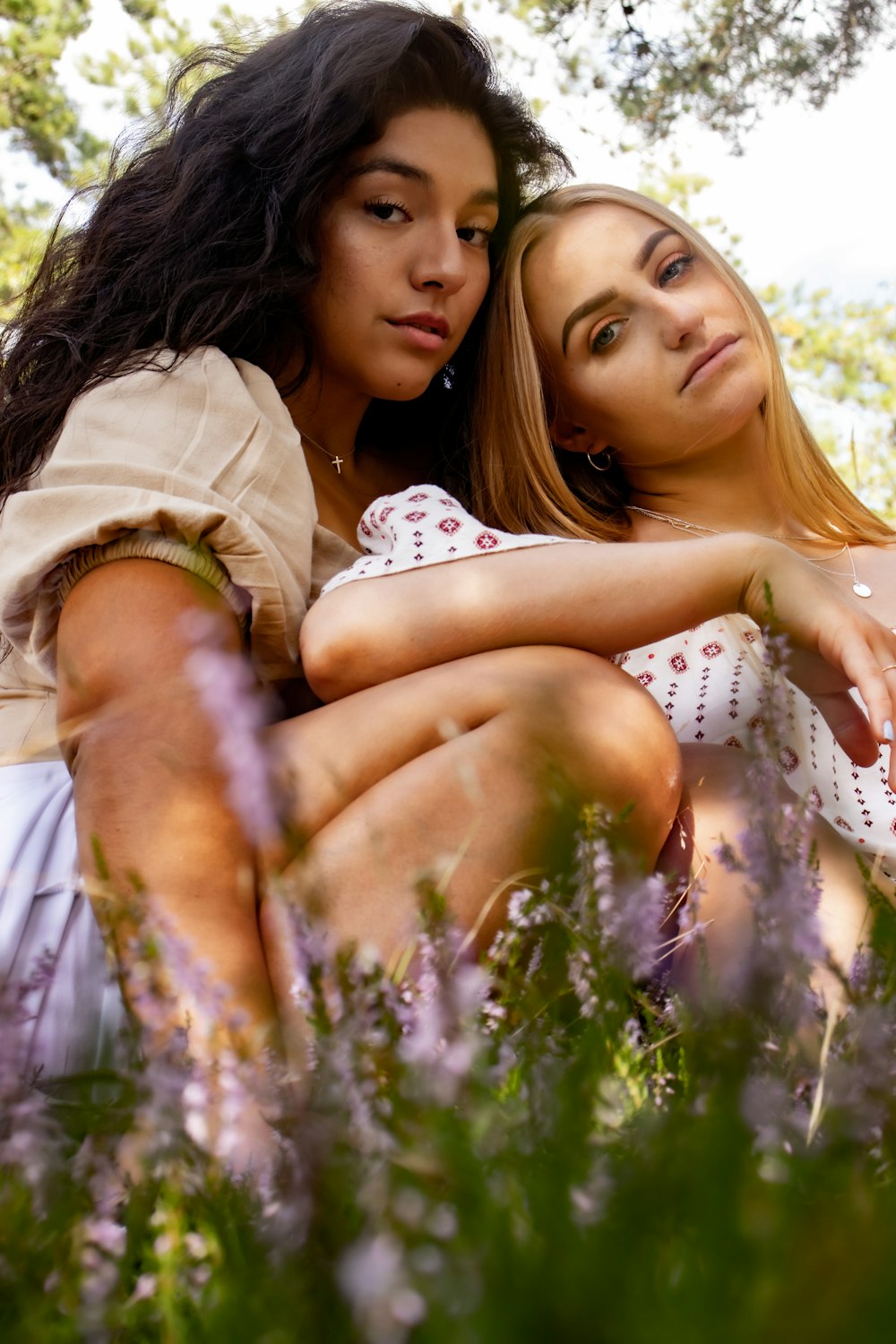 2 women lying on green grass field during daytime