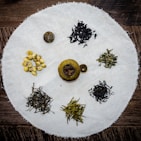 Brightly colored tea blends with flower petals and herbs arranged in small bowls.