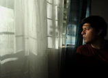 A thoughtful adult sitting by a window with soft natural light, reflecting on personal growth and meaning.