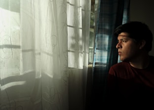 A serene scene of a woman journaling by a window, sunlight filtering through sheer curtains.