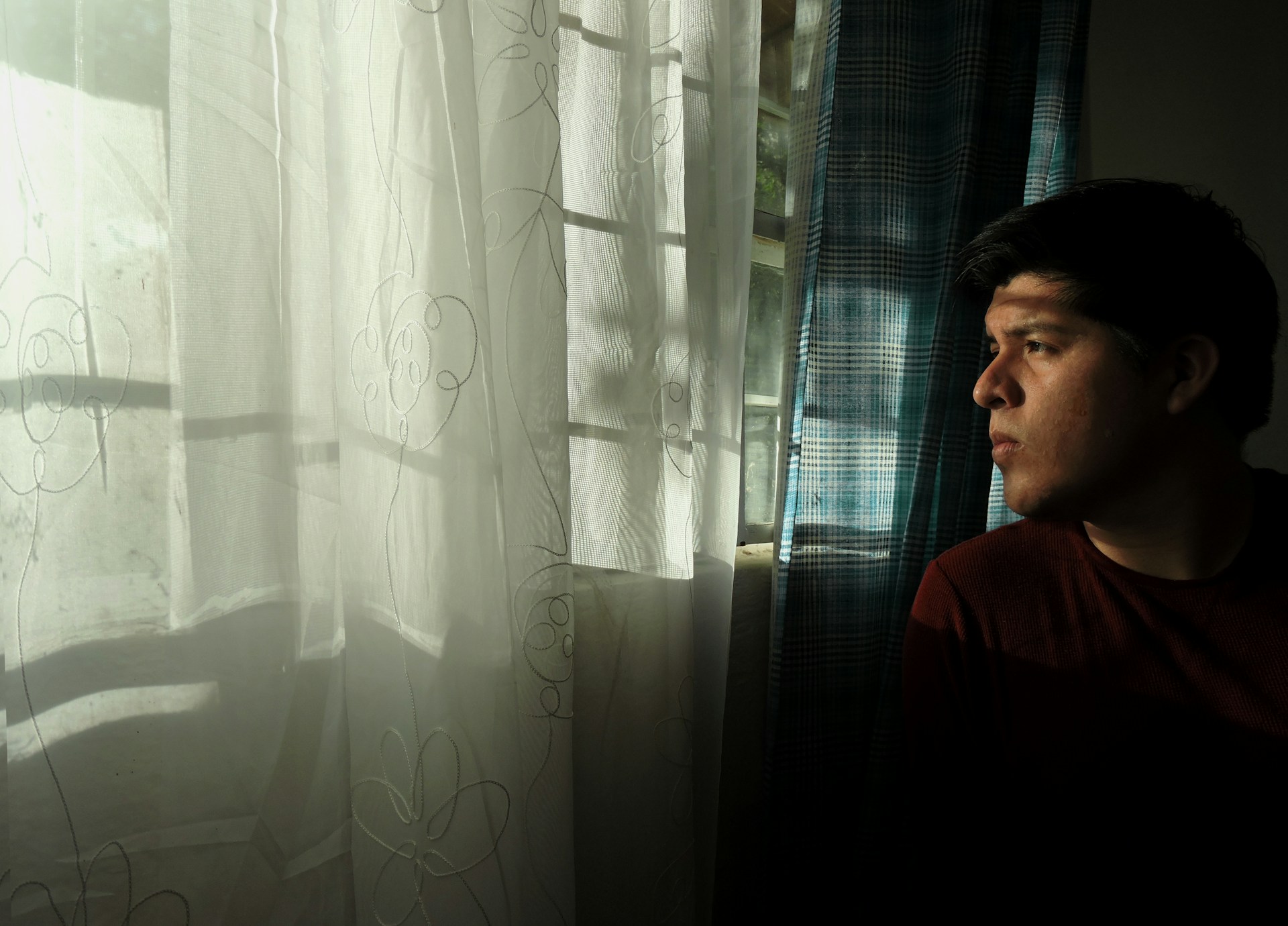 A serene moment of olysera lost in thought, pen in hand, composing lyrics by a window with soft natural light.