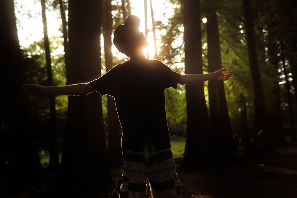 man in black t-shirt standing in forest during daytime
