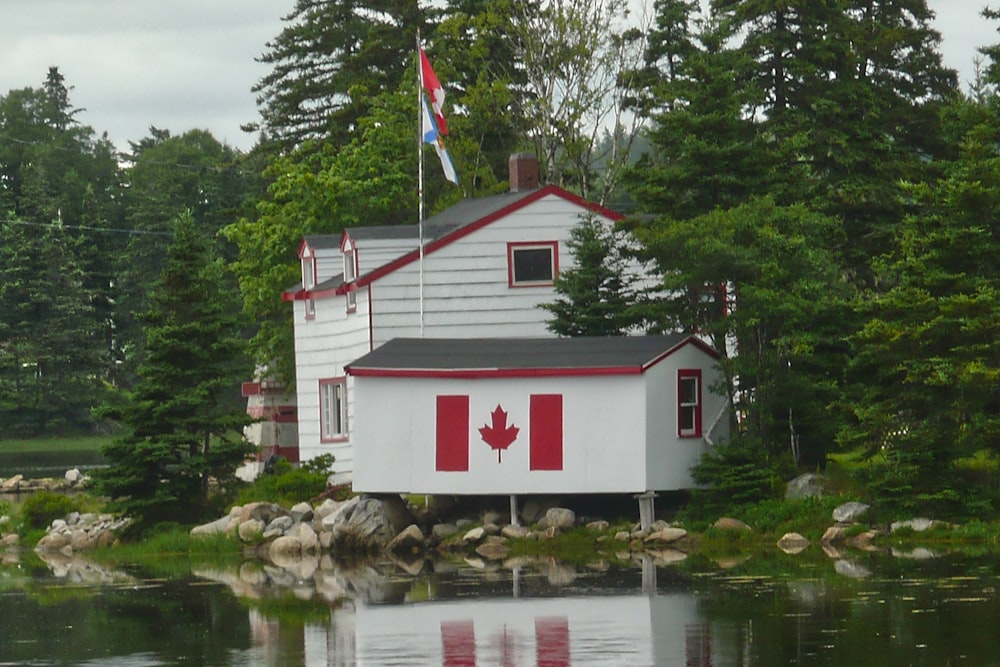 white and red wooden house near body of water during daytime