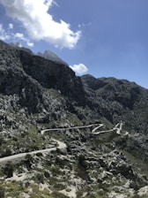 A winding road cutting through the rugged Atlas Mountains under a bright blue sky.