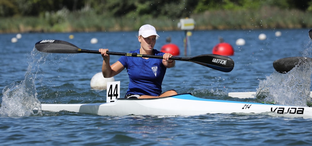 man in blue and white wet suit riding white and red kayak