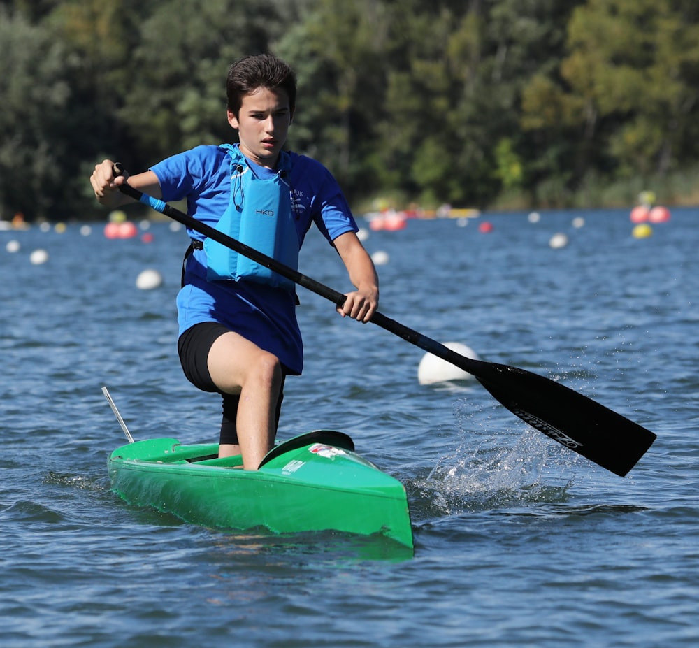 man in blue and black wet suit riding green kayak on river during daytime