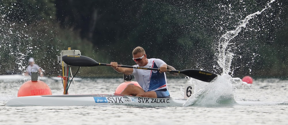 man in red and white life vest riding blue kayak on river during daytime