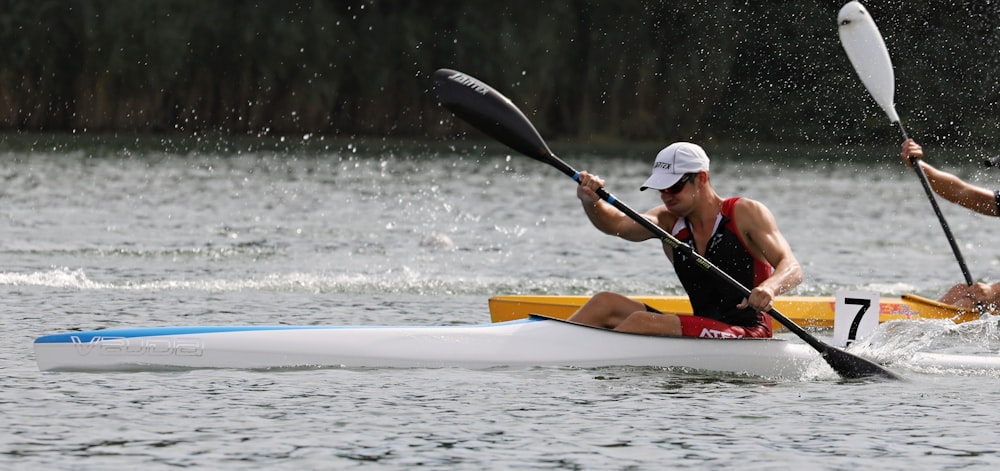 man in white hat riding yellow kayak on water during daytime