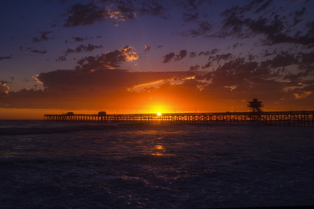 silhouette of dock on sea during sunset