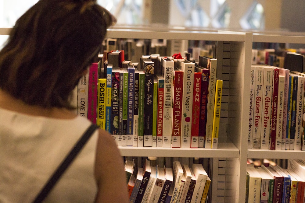 woman in black tank top standing near books