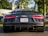 A sleek, black sports car is parked on the road. It features distinctive red taillights, a Virginia license plate, and a visible Audi R8 badge. The vehicle is surrounded by an outdoor setting with trees and a blurred background.
