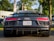 A sleek, black sports car is parked on the road. It features distinctive red taillights, a Virginia license plate, and a visible Audi R8 badge. The vehicle is surrounded by an outdoor setting with trees and a blurred background.