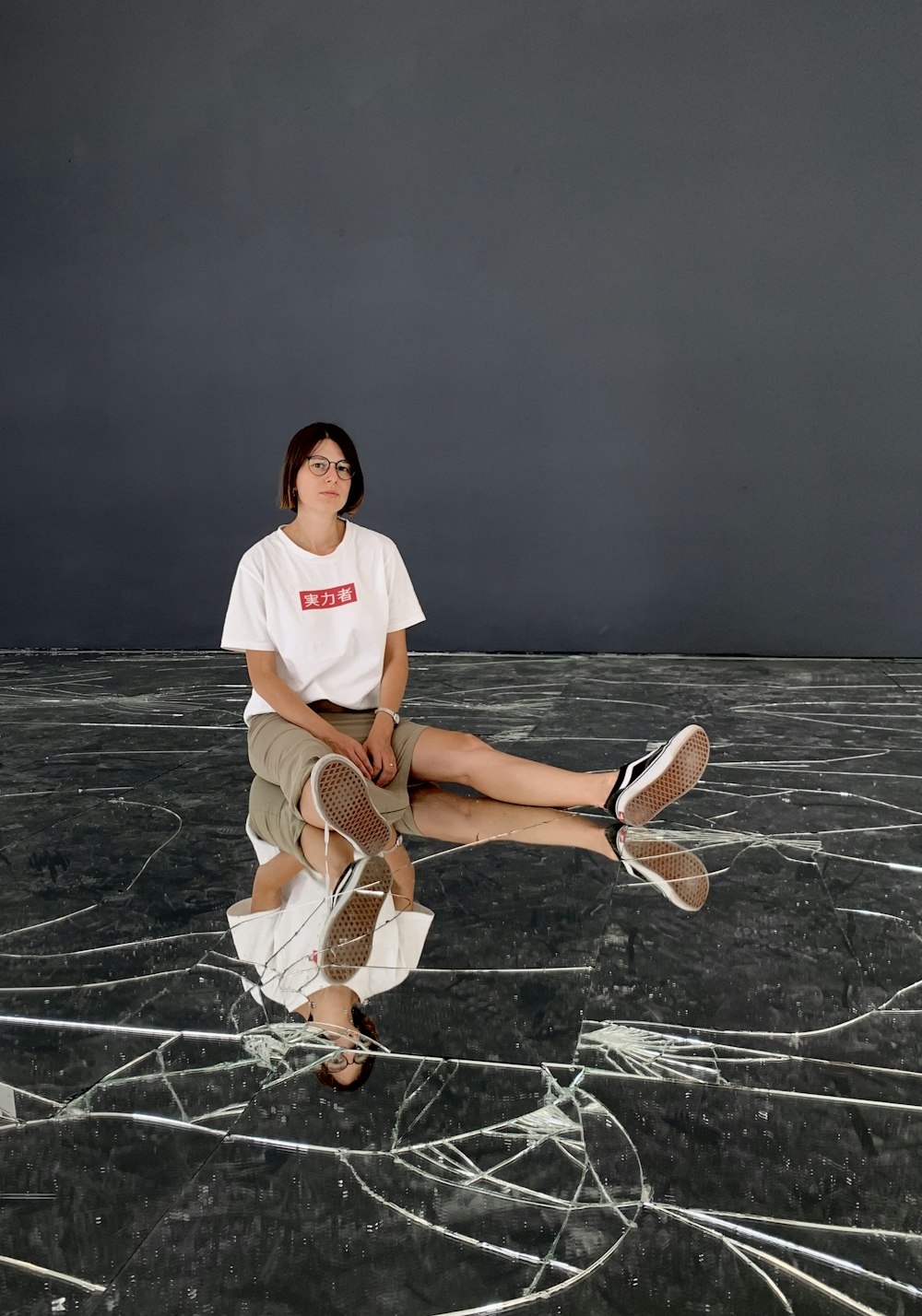 woman in white t-shirt and brown skirt sitting on gray concrete floor