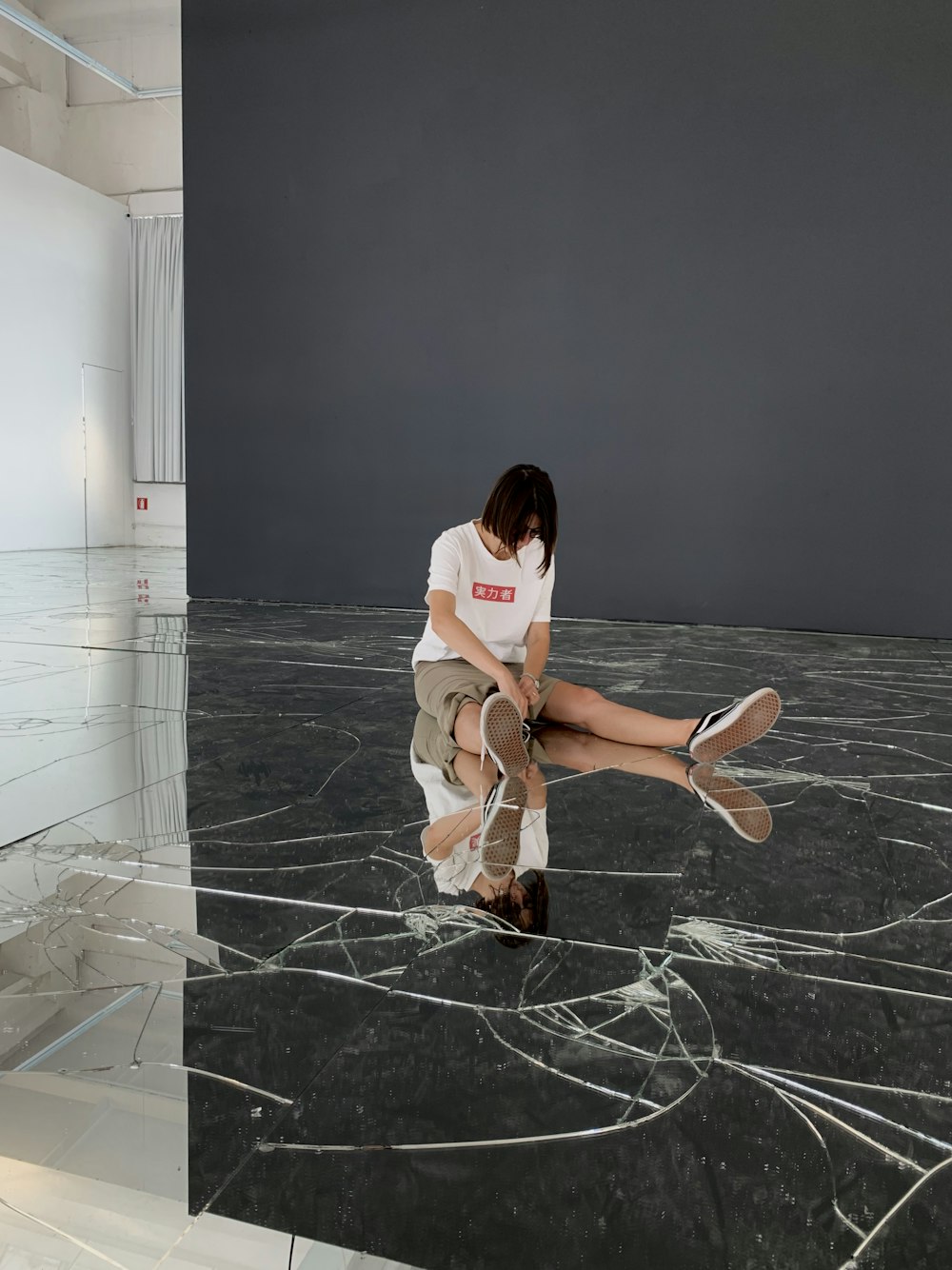 woman in white t-shirt and brown skirt sitting on black floor tiles