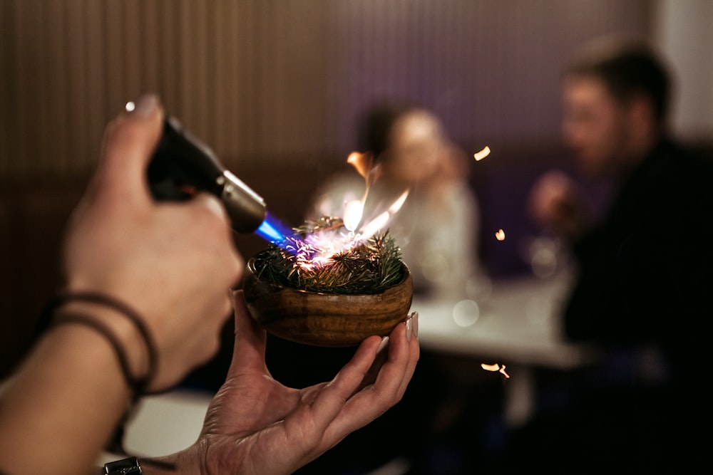 person holding lighted candle in brown round container