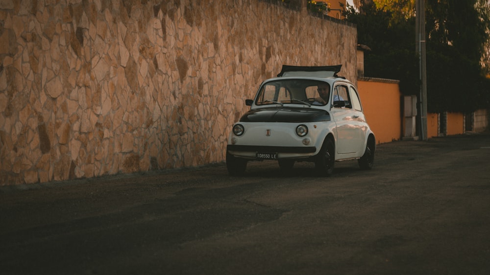 white car parked beside brown brick wall