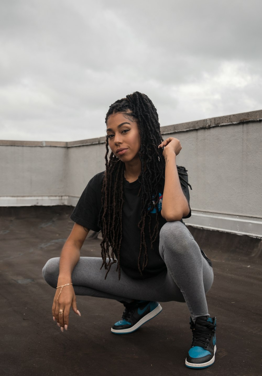 woman in black t-shirt and gray pants sitting on concrete wall during daytime