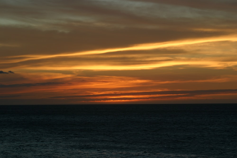 body of water under cloudy sky during sunset