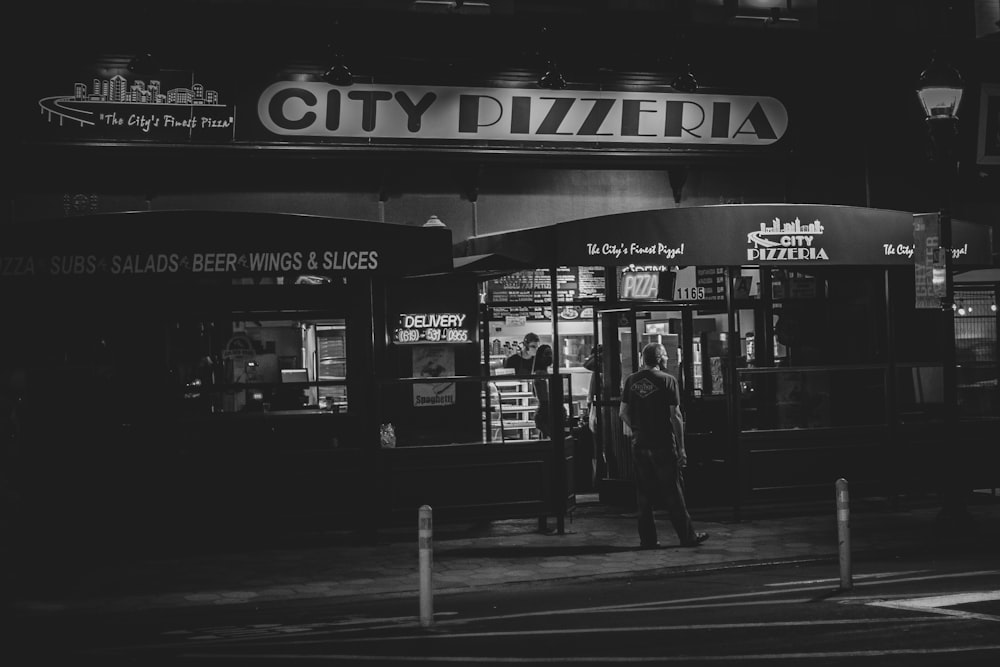 grayscale photo of man and woman walking on sidewalk