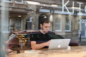 Smiling business owner checking transactions on a laptop in a cozy cafe.