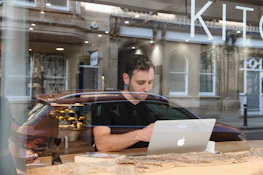 Smiling business owner checking transactions on a laptop in a cozy cafe.