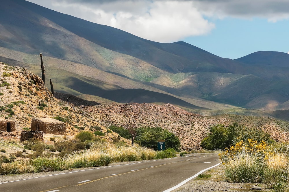 gray asphalt road near green grass field and mountain during daytime