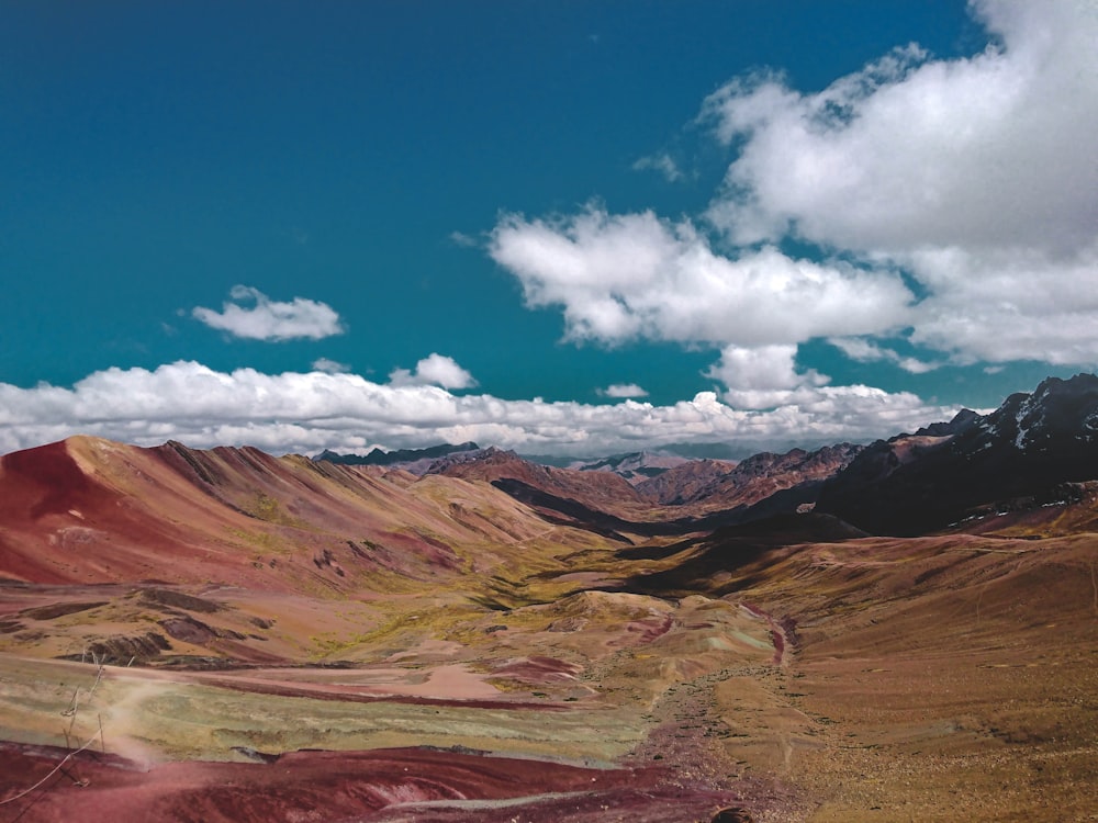 brown and gray mountains under blue sky and white clouds during daytime