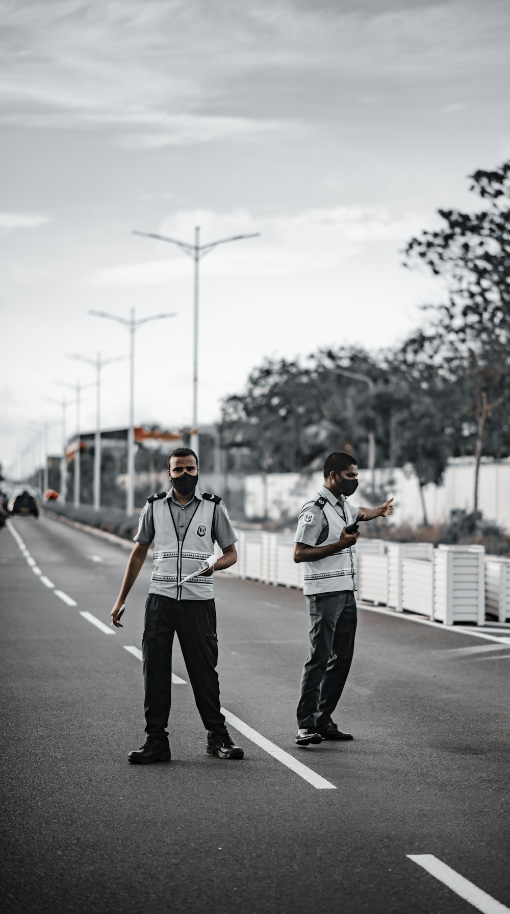 man in white shirt and black pants standing on road during daytime