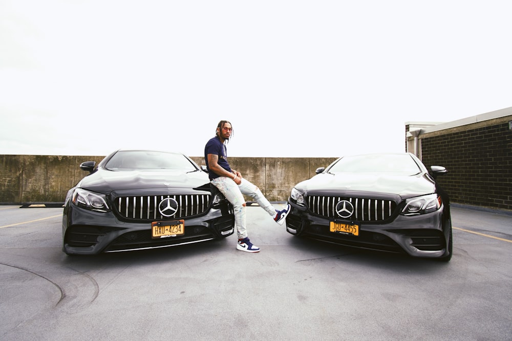 man in black t-shirt sitting on black mercedes benz car