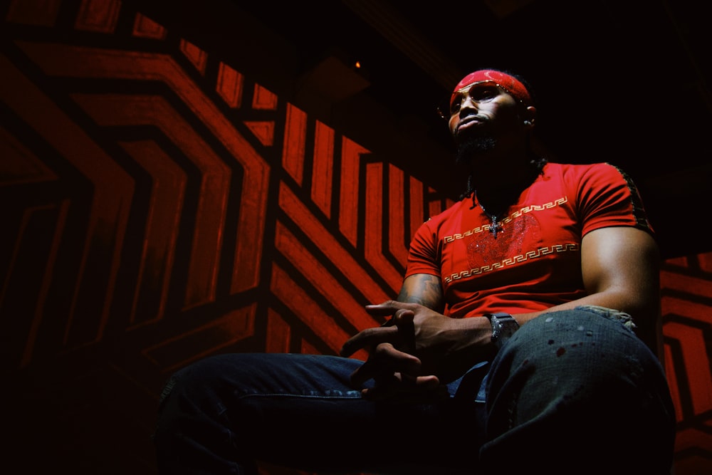 man in red shirt and blue denim jeans sitting on stairs