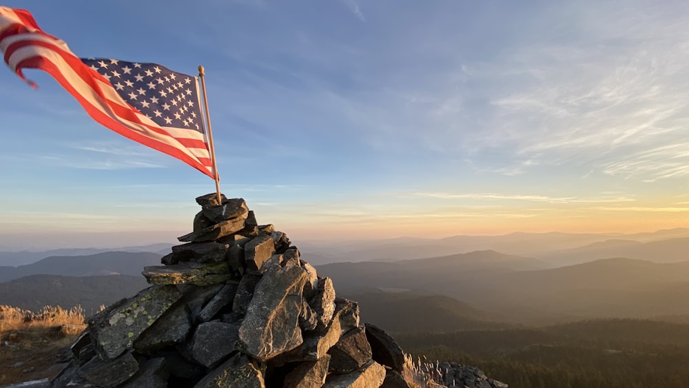 us a flag on rock formation during daytime