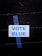 A white sign with the words 'VOTE BLUE' in blue capital letters is taped to a black brick wall using a piece of blue painter's tape.