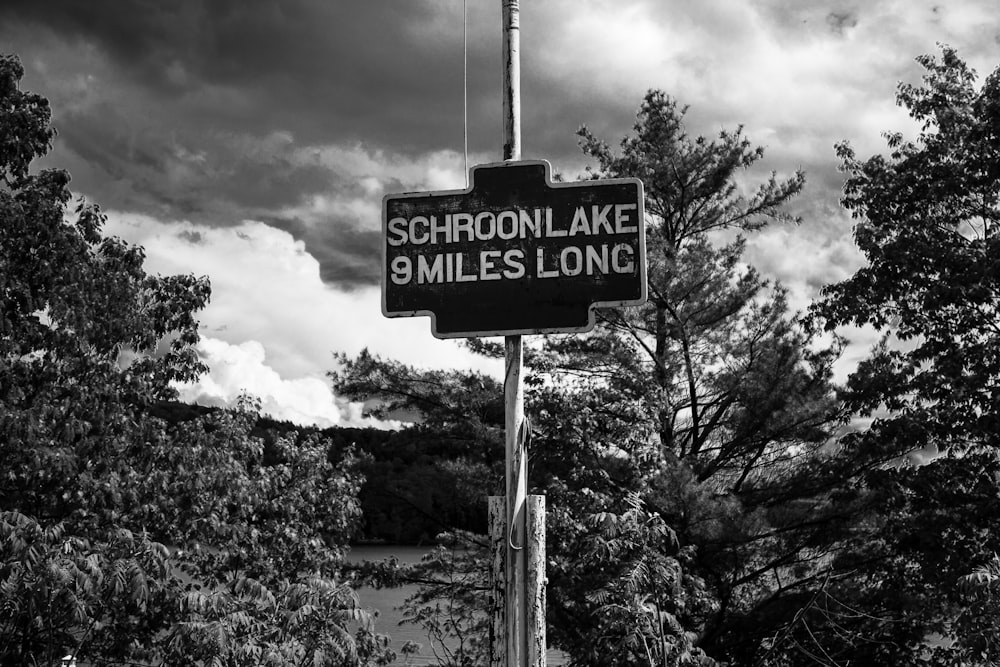 a black and white photo of a sign that says schroon lake 3 miles