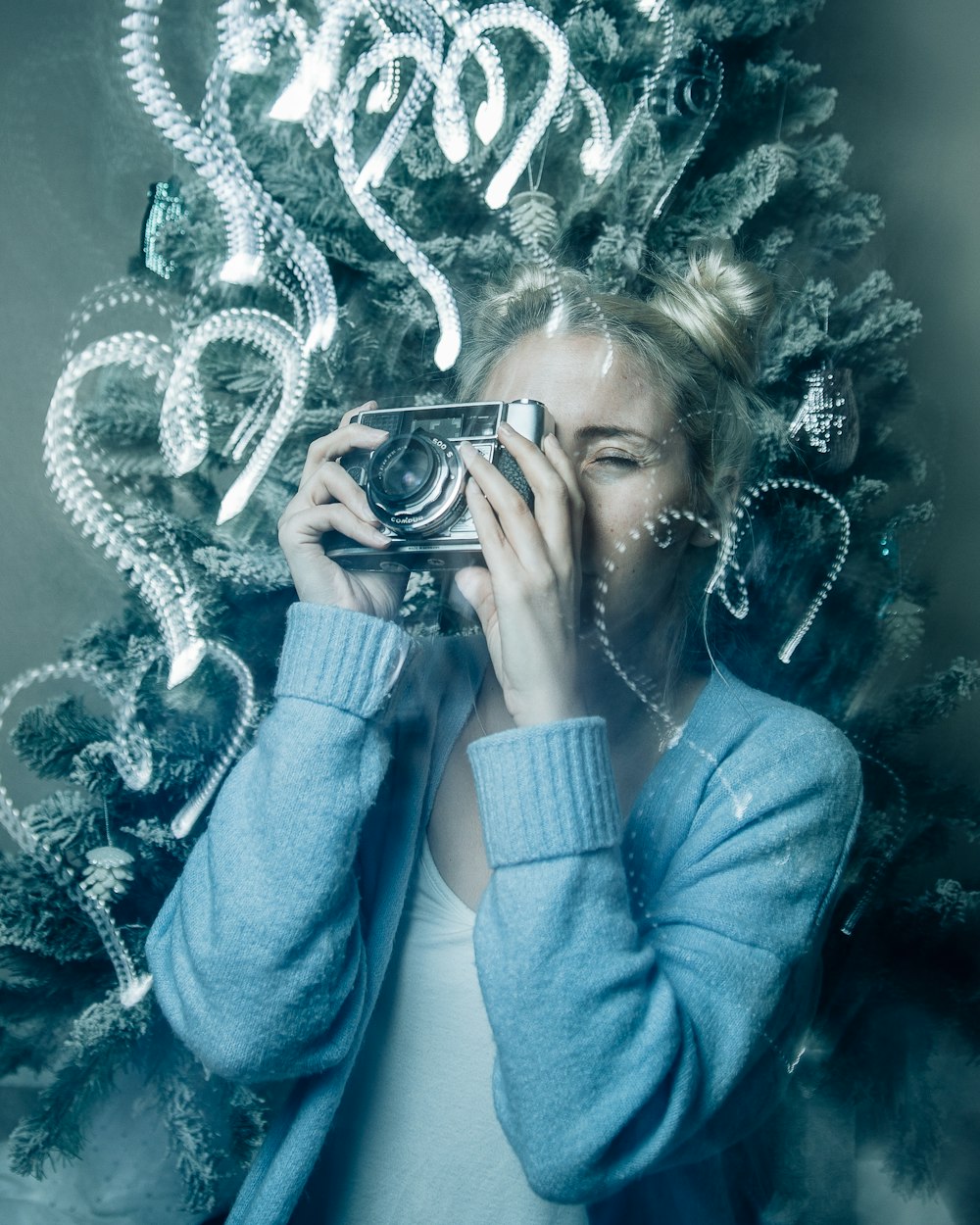 woman in blue sweater holding black camera