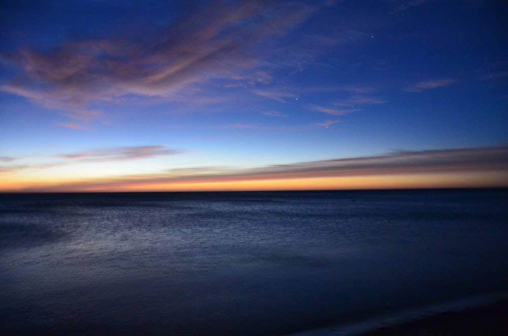 a view of the ocean at sunset from a beach