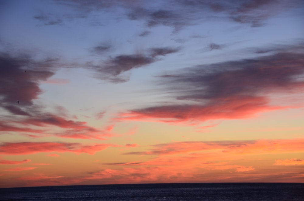 body of water under cloudy sky during sunset