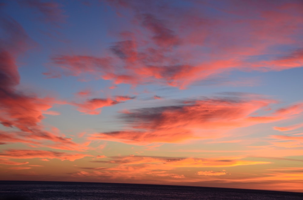 body of water under cloudy sky during sunset