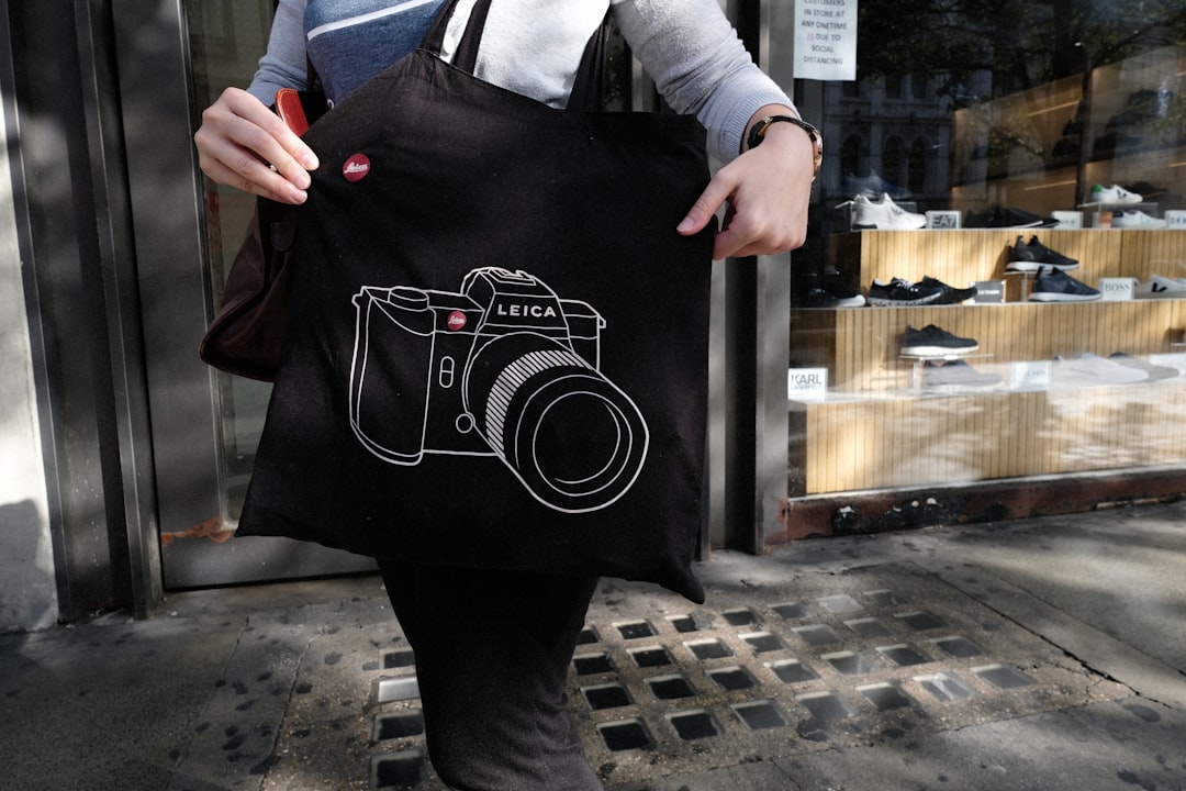 woman in black apron holding black and red tote bag
