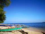 Traditional fishing boats resting on the sandy shore under a clear blue sky.