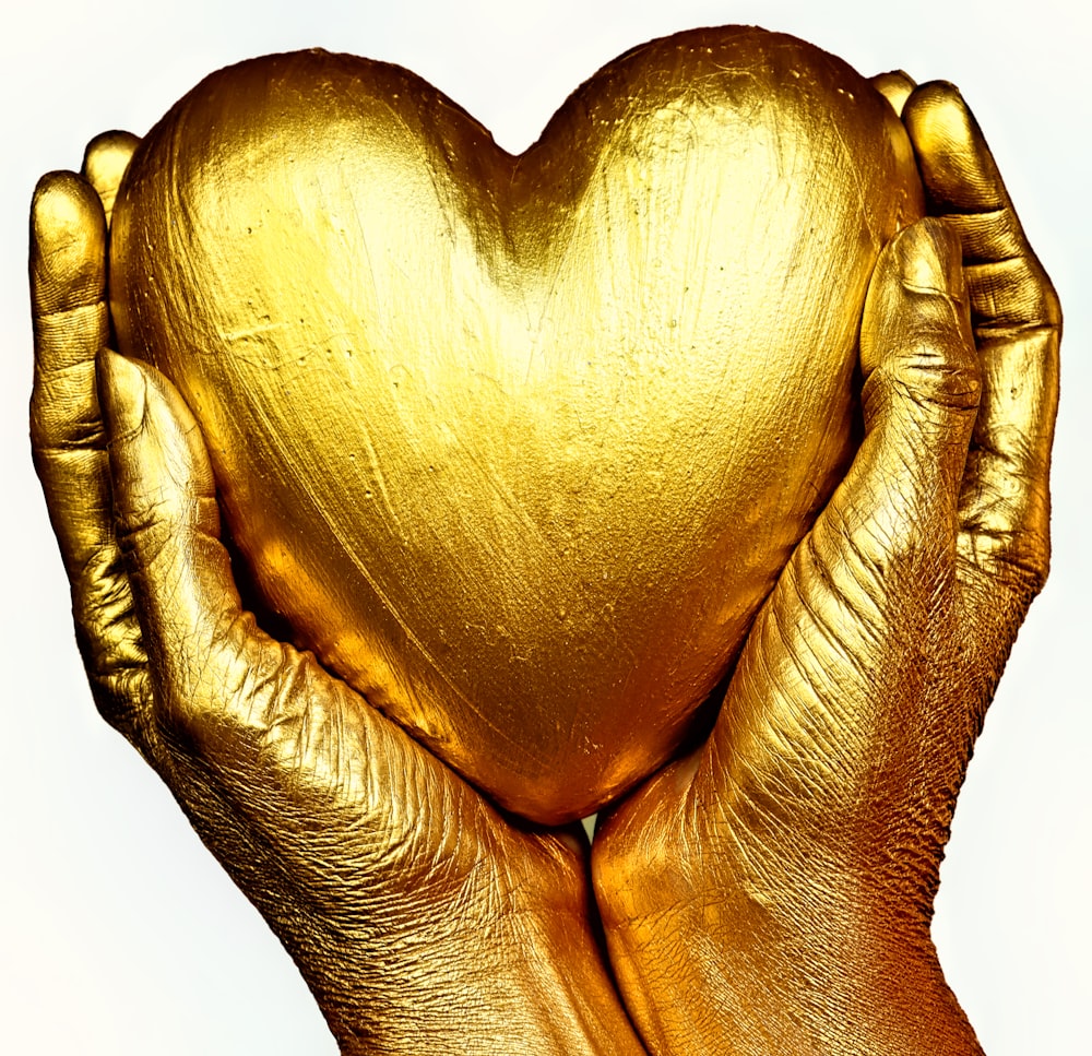 gold heart shaped ornament on persons hand