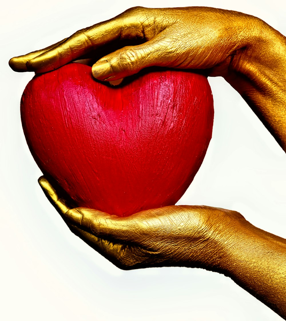 person holding red heart ornament