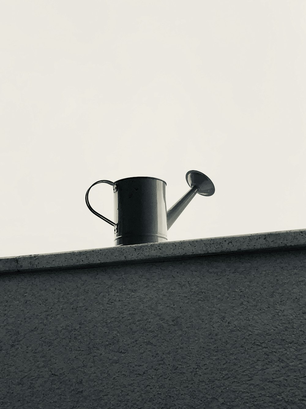 灰色のコンクリートの壁に黒と白のセラミックマグカップ