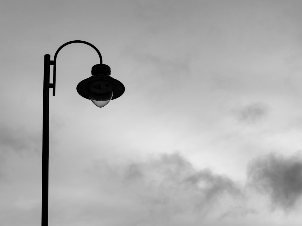 grayscale photo of light bulb under cloudy sky