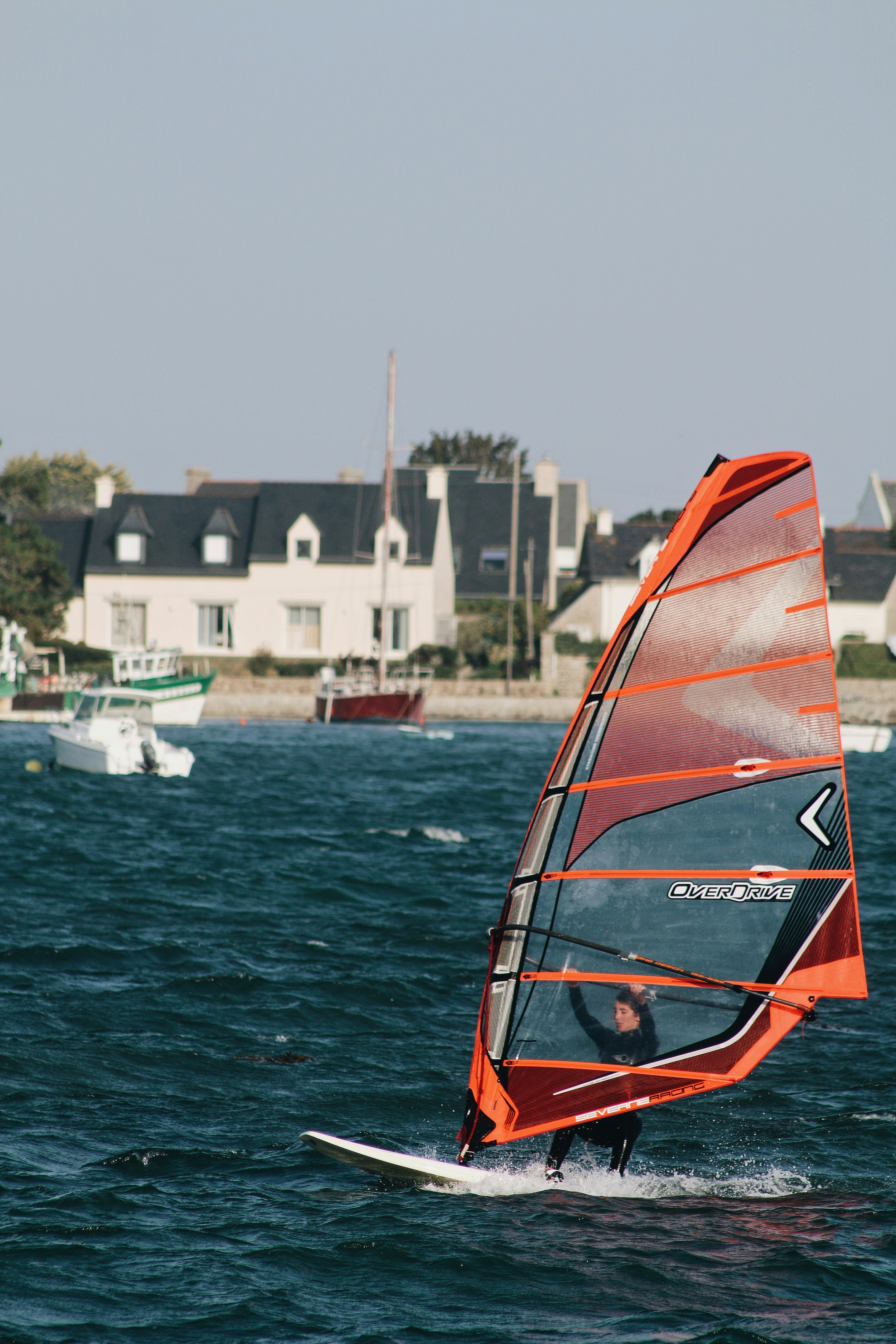 orange and black sail boat on sea during daytime