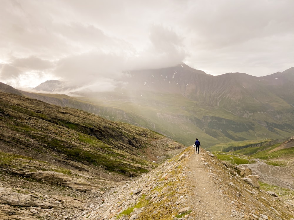 person walking on brown dirt road during daytime